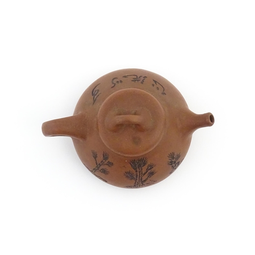 102 - A Chinese Yixing teapot with incised tree and script detail. Character marks under and to underside ... 