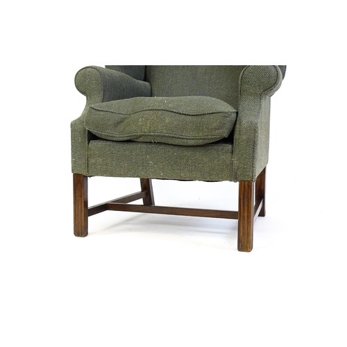 229 - An early 20thC wingback armchair raised on chamfered front legs united by a H stretcher. 33