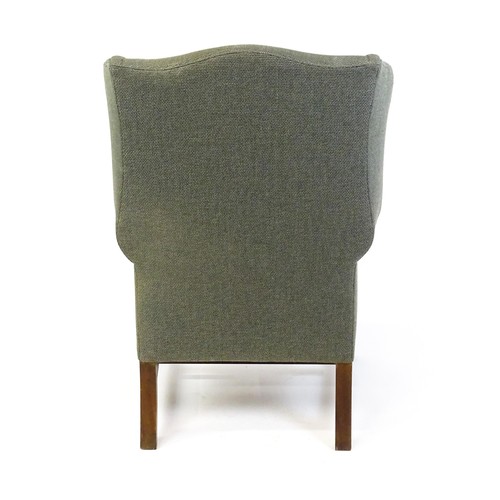 229 - An early 20thC wingback armchair raised on chamfered front legs united by a H stretcher. 33