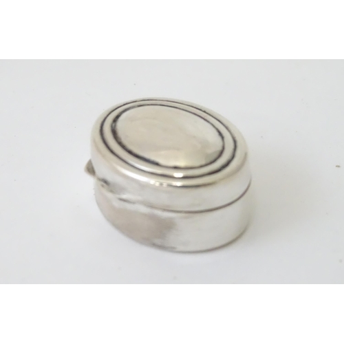 425 - A white metal pill box of oval form with hinged lid. Approx. 1 1/8