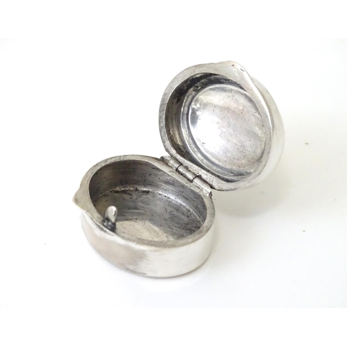 425 - A white metal pill box of oval form with hinged lid. Approx. 1 1/8