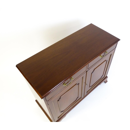 604 - A mahogany cabinet with a moulded top above two short drawers and two panelled cupboard, the cabinet... 