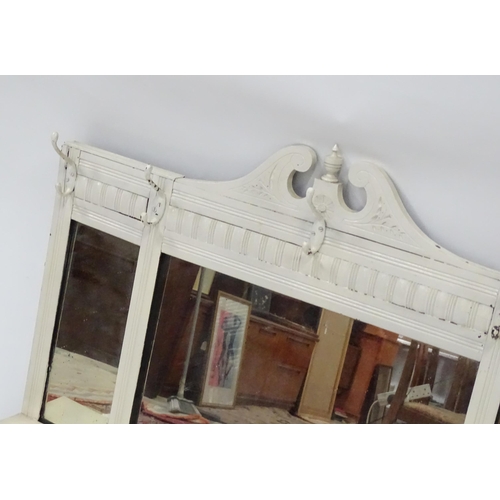 606 - An Edwardian painted mirror with a carved pediment and two shelves. 44