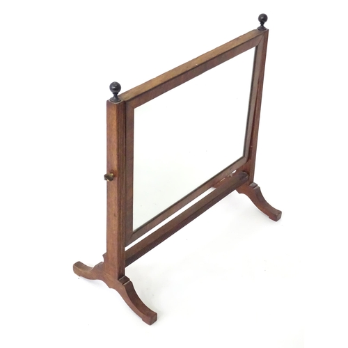 786 - A 19thC mahogany toilet mirror, the adjustable frame with rectangular glass supported by a fluted st... 