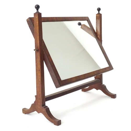 786 - A 19thC mahogany toilet mirror, the adjustable frame with rectangular glass supported by a fluted st... 