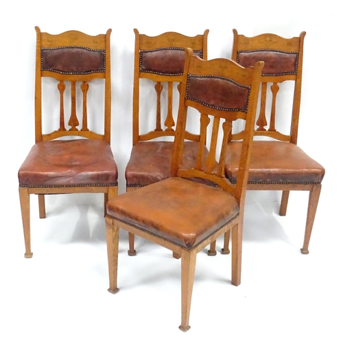 908 - Four Art Nouveau oak dining chairs, with flower formed back splats, inlaid backrests, leather back r... 