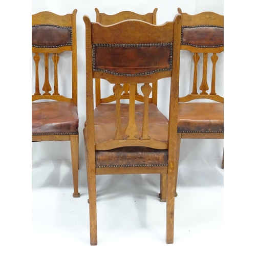 908 - Four Art Nouveau oak dining chairs, with flower formed back splats, inlaid backrests, leather back r... 