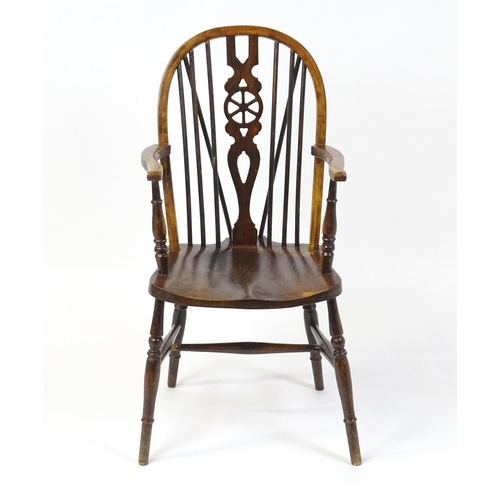 189 - An early 20thC wheel back Windsor chair, having a shaped seat and raised on turned tapering legs uni... 