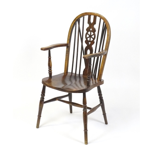 189 - An early 20thC wheel back Windsor chair, having a shaped seat and raised on turned tapering legs uni... 