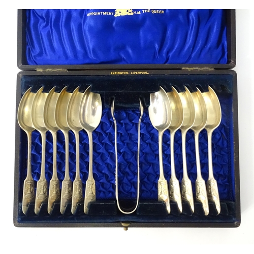 446 - A cased set of twelve silver plate spoons with tongs en suite by Elkington, the handles decorated wi... 