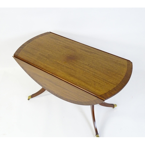 659 - A mid / late 20thC mahogany drop flap dining table, having a crossbanded and reeded rotating top rai... 