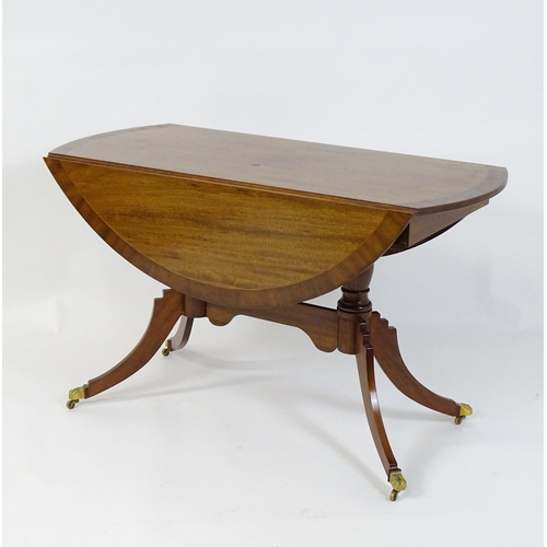 659 - A mid / late 20thC mahogany drop flap dining table, having a crossbanded and reeded rotating top rai... 