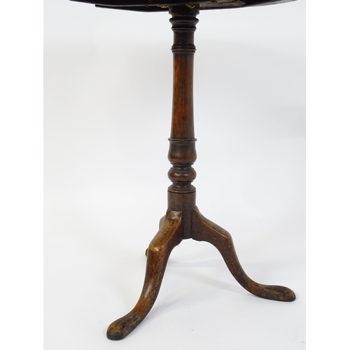 677 - An 18thC mahogany tripod table raised on a turned pedestal and three cabriole legs. 24