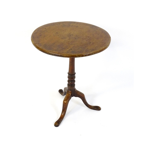 677 - An 18thC mahogany tripod table raised on a turned pedestal and three cabriole legs. 24