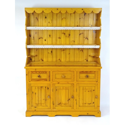 71 - A pine dresser with a three tier plate rack above three short drawers and three panelled cupboards w... 