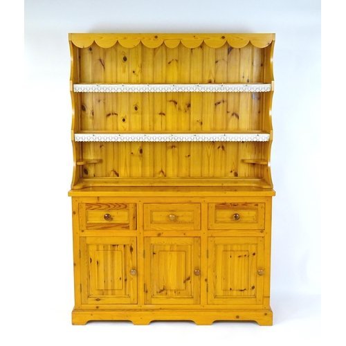 71 - A pine dresser with a three tier plate rack above three short drawers and three panelled cupboards w... 