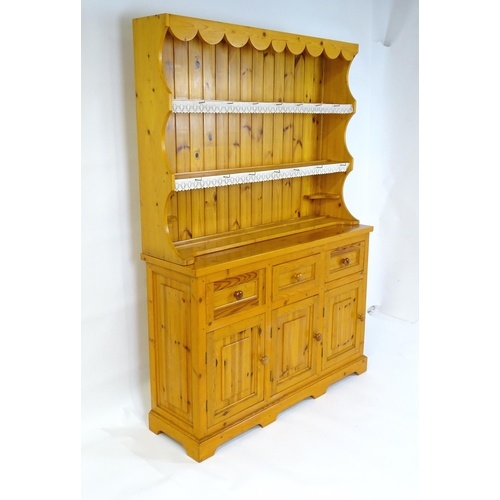 71 - A pine dresser with a three tier plate rack above three short drawers and three panelled cupboards w... 