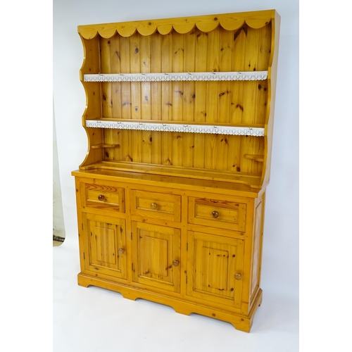 71 - A pine dresser with a three tier plate rack above three short drawers and three panelled cupboards w... 