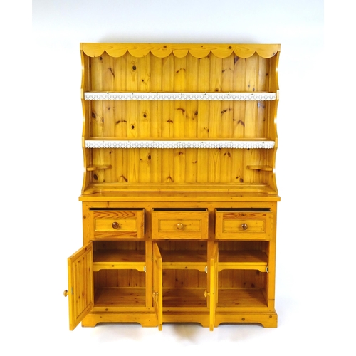 71 - A pine dresser with a three tier plate rack above three short drawers and three panelled cupboards w... 