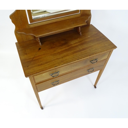 721 - An early 20thC mahogany dressing table with a shaped upstand, shelf and arched mirror. The top havin... 