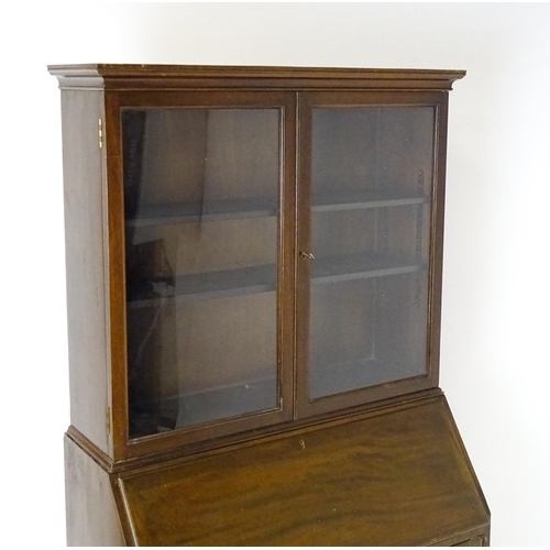 732 - A mid 20hC mahogany bureau bookcase by Russell of Broadway. The bookcase with a moulded cornice abov... 