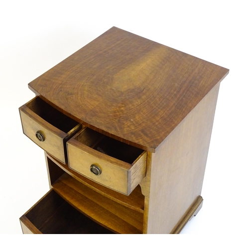 884 - A walnut veneered chest with three small drawers and two shelves raised on short bracket feet. 20