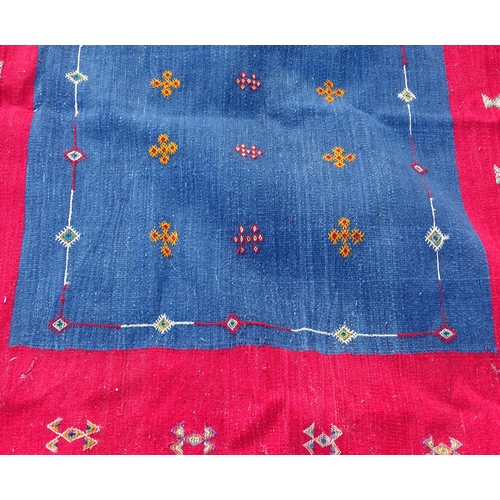 16 - Carpet / Rug: A hand made flat weave wall hanging with central blue ground surrounded by a large red... 