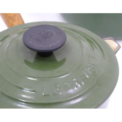 613 - Four green graduated Le Creuset saucepans. Together with cast pot stands (8)