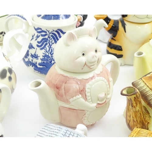 715 - A quantity of teapots to include novelty bride and groom pigs, cottages, treacle glaze examples, etc... 