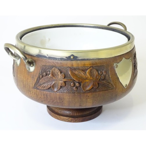 801 - An early 20thC oak pedestal salad bowl with carved foliate decoration and brass handles and mounts. ... 