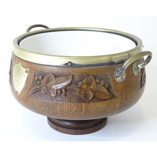 801 - An early 20thC oak pedestal salad bowl with carved foliate decoration and brass handles and mounts. ... 