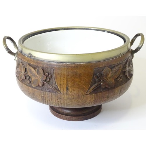 801 - An early 20thC oak pedestal salad bowl with carved foliate decoration and brass handles and mounts. ... 