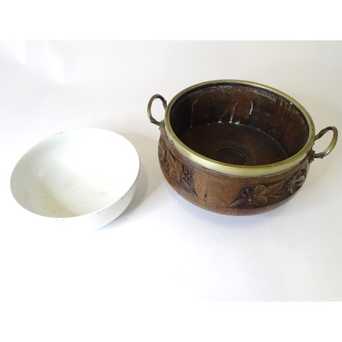 801 - An early 20thC oak pedestal salad bowl with carved foliate decoration and brass handles and mounts. ... 