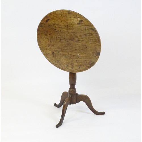 152 - An 18thC oak tripod table with a circular top above a turned pedestal and three cabriole legs. 27