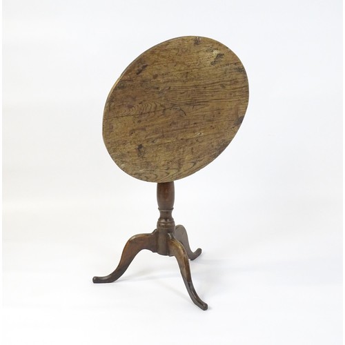 152 - An 18thC oak tripod table with a circular top above a turned pedestal and three cabriole legs. 27