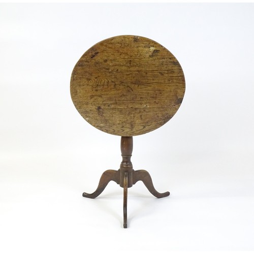 152 - An 18thC oak tripod table with a circular top above a turned pedestal and three cabriole legs. 27