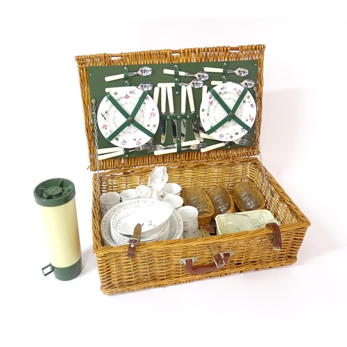 630 - A wicker picnic basket containing plastic plates, bowls, mugs, etc. with floral decoration, cutlery,... 