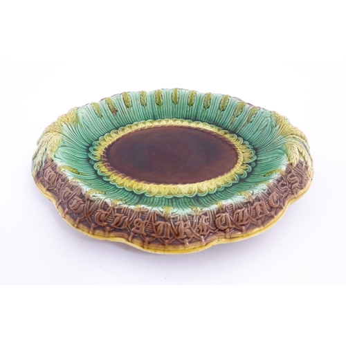 142 - A Victorian majolica bread plate, the inner rim decorated with wheat sheaves, the outer edge bearing... 