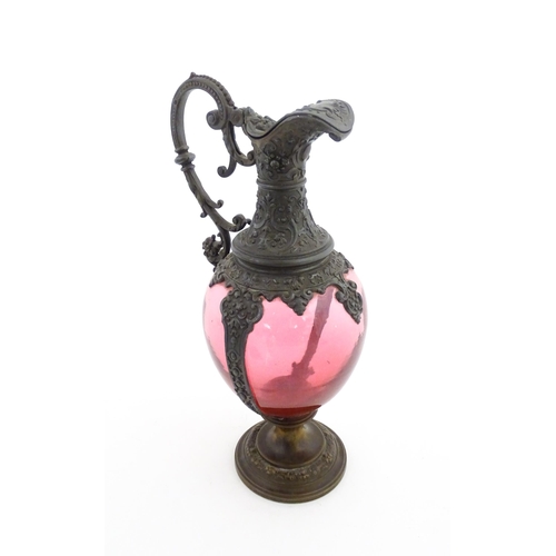 233 - A Victorian cranberry glass claret jug with decorative metal mounts and handle. Approx. 13