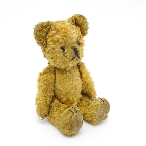 945 - Toy: An early 20thC teddy bear with stitched nose and mouth and articulated limbs. Approx. 9 1/4