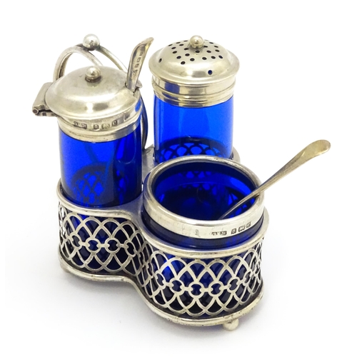 244 - A silver cruet set with blue glass bottles, comprising stand, salt, pepper and mustard, hallmarked B... 