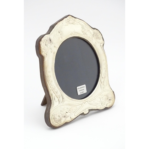 374 - An easel back photograph frame with silver surround with Art Nouveau style decoration depicting wate... 