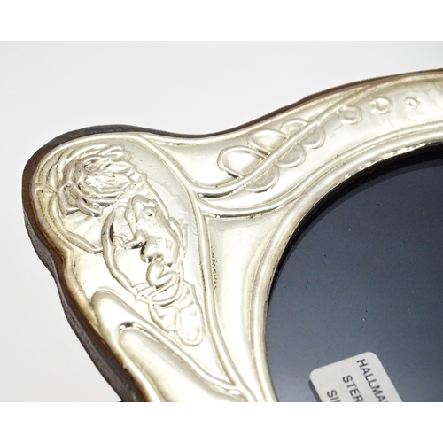 374 - An easel back photograph frame with silver surround with Art Nouveau style decoration depicting wate... 