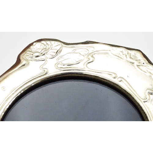 374 - An easel back photograph frame with silver surround with Art Nouveau style decoration depicting wate... 