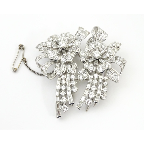 743 - A diamond double clip brooch, the clips with flower and bow detail set with a profusion of baguette ... 