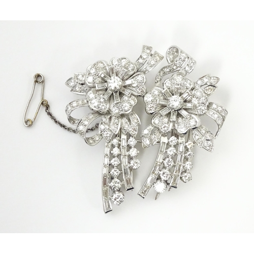 743 - A diamond double clip brooch, the clips with flower and bow detail set with a profusion of baguette ... 