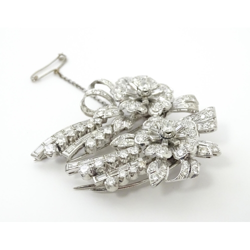 743 - A diamond double clip brooch, the clips with flower and bow detail set with a profusion of baguette ... 