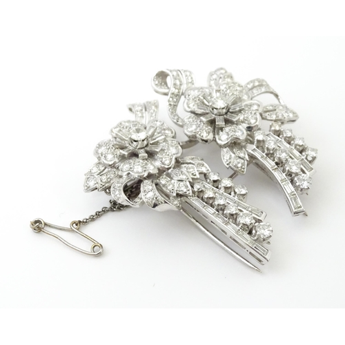 743 - A diamond double clip brooch, the clips with flower and bow detail set with a profusion of baguette ... 