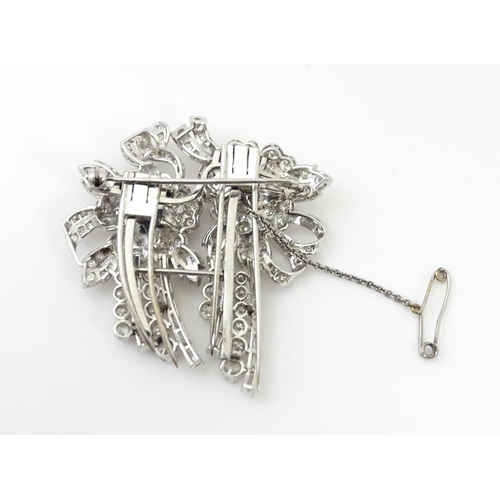 743 - A diamond double clip brooch, the clips with flower and bow detail set with a profusion of baguette ... 