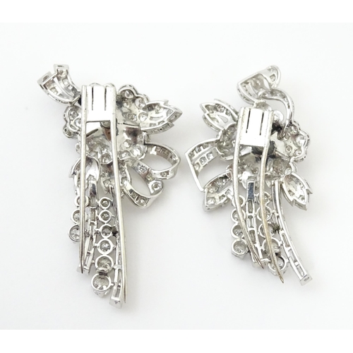 743 - A diamond double clip brooch, the clips with flower and bow detail set with a profusion of baguette ... 